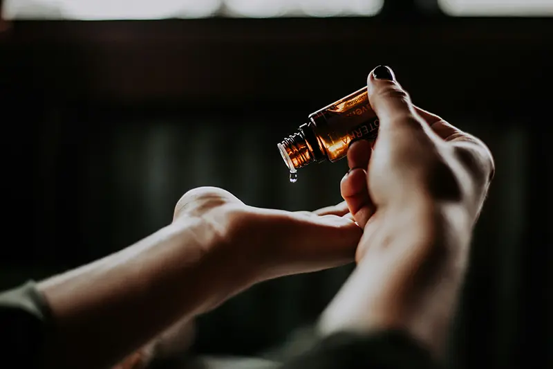 Mains tenant une fiole d'extrait de parfum